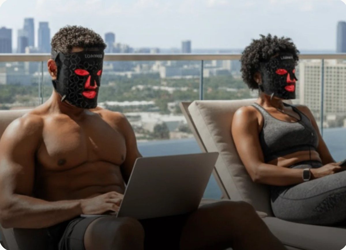 Two people wearing Lumara red-light masks on a rooftop terrace